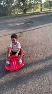 Child riding the red wiggle car outside