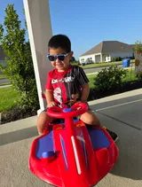 Child riding the red and blue wiggle car on the porch